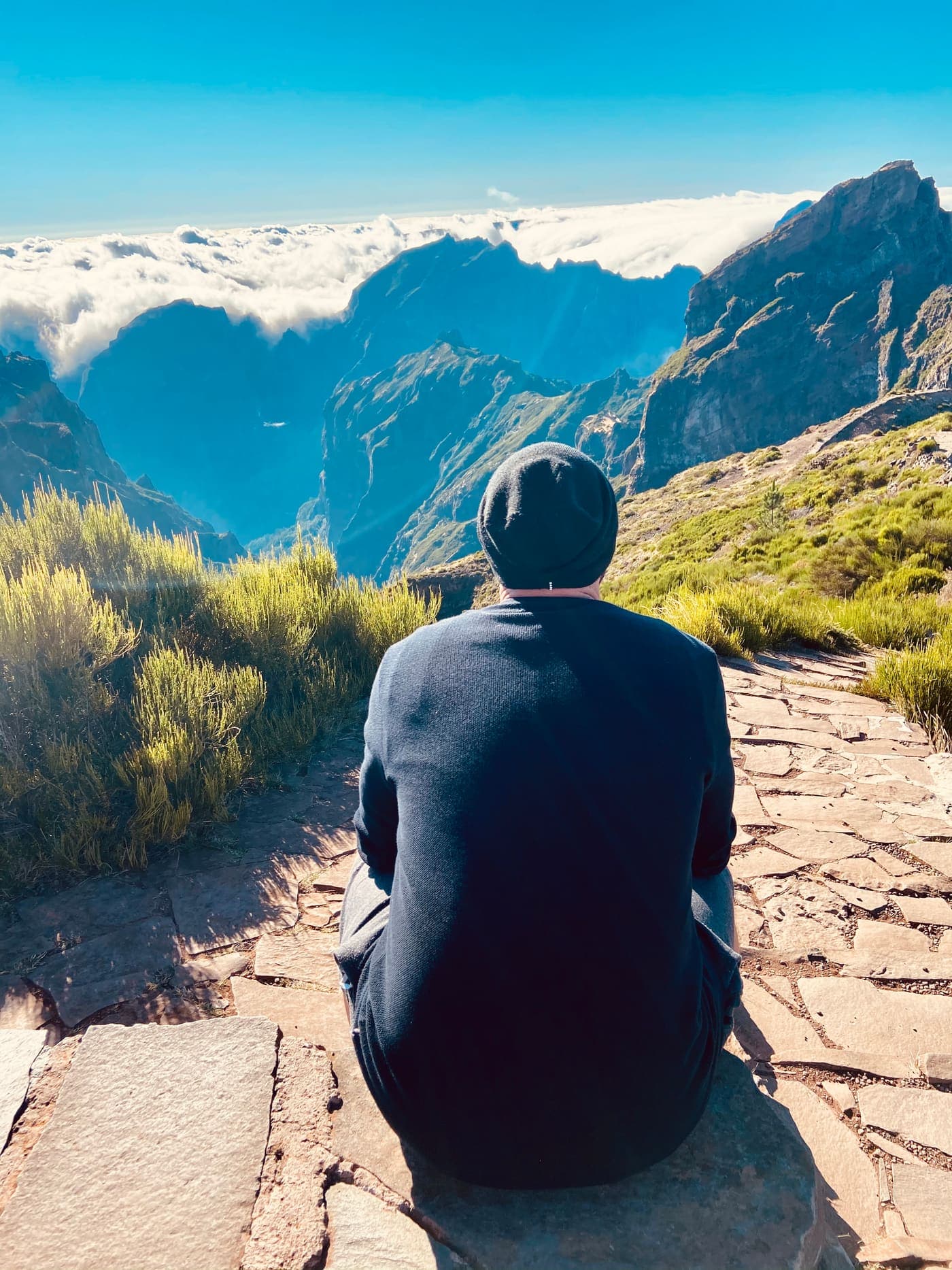 Ivo Deutschmann seen from behind on a mountain ridge above the clouds