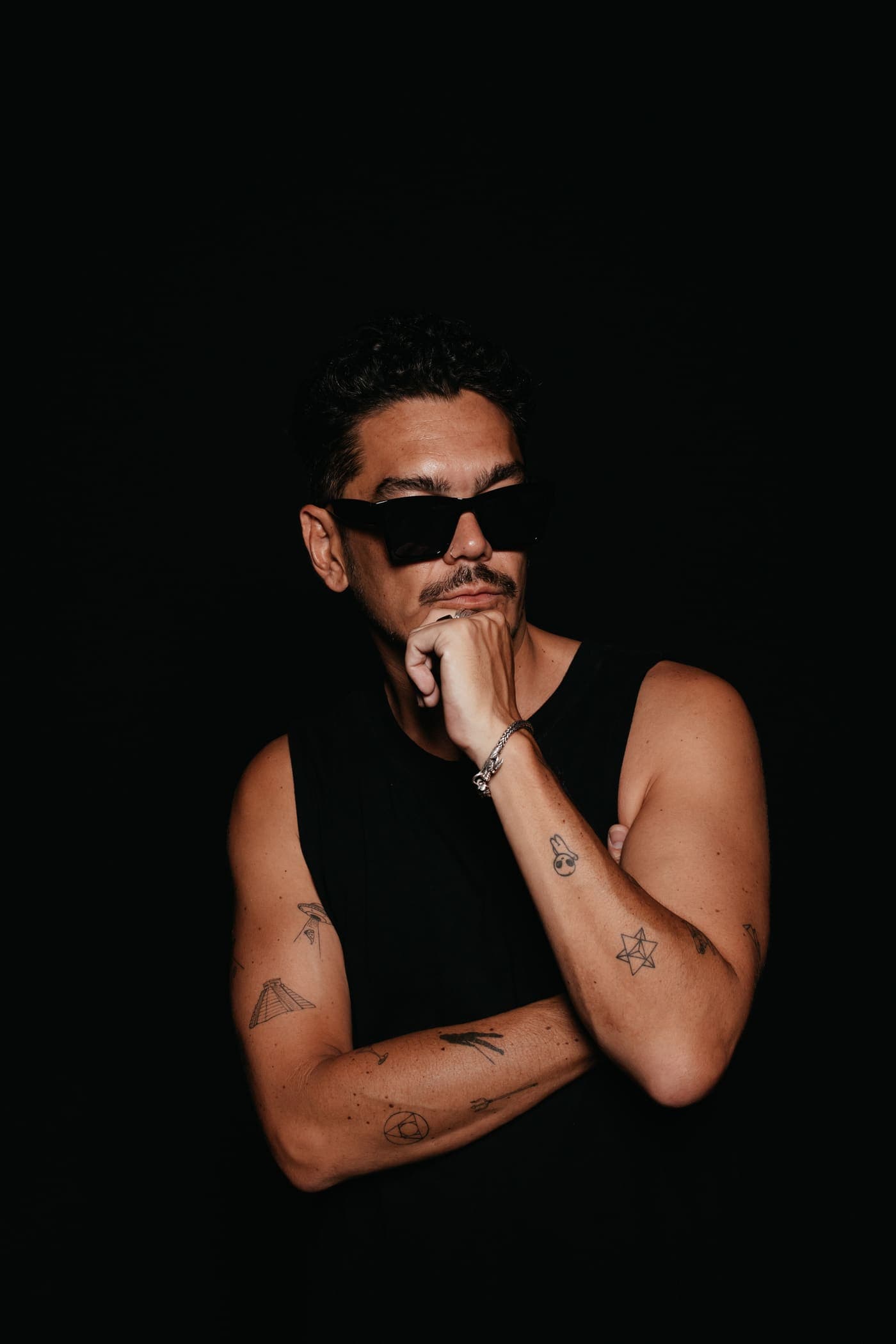 Kaiser Waldon in sunglasses and a black vest against a black background
