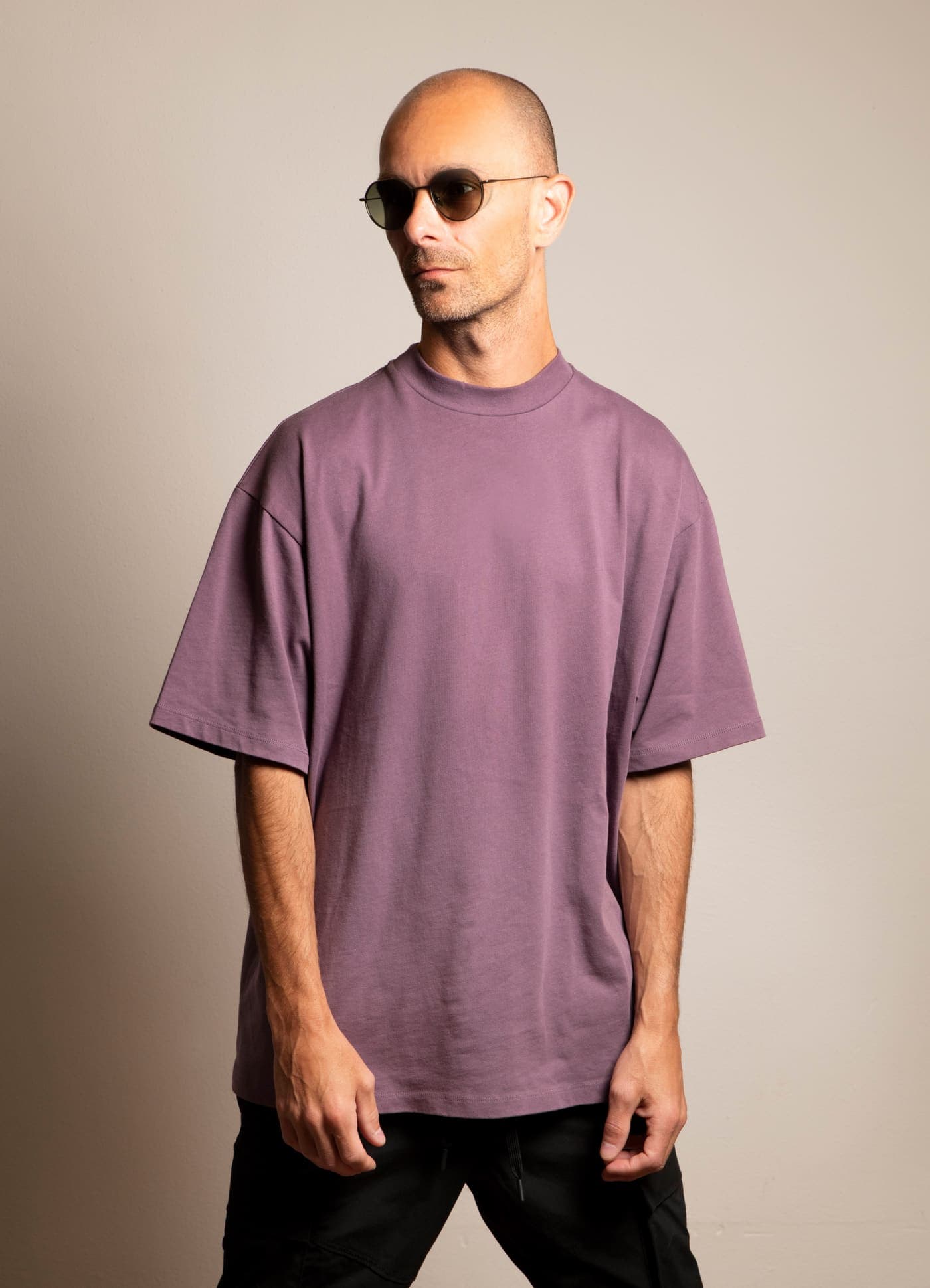 Max Hefele in sunglasses and an oversized shirt against a pale wall