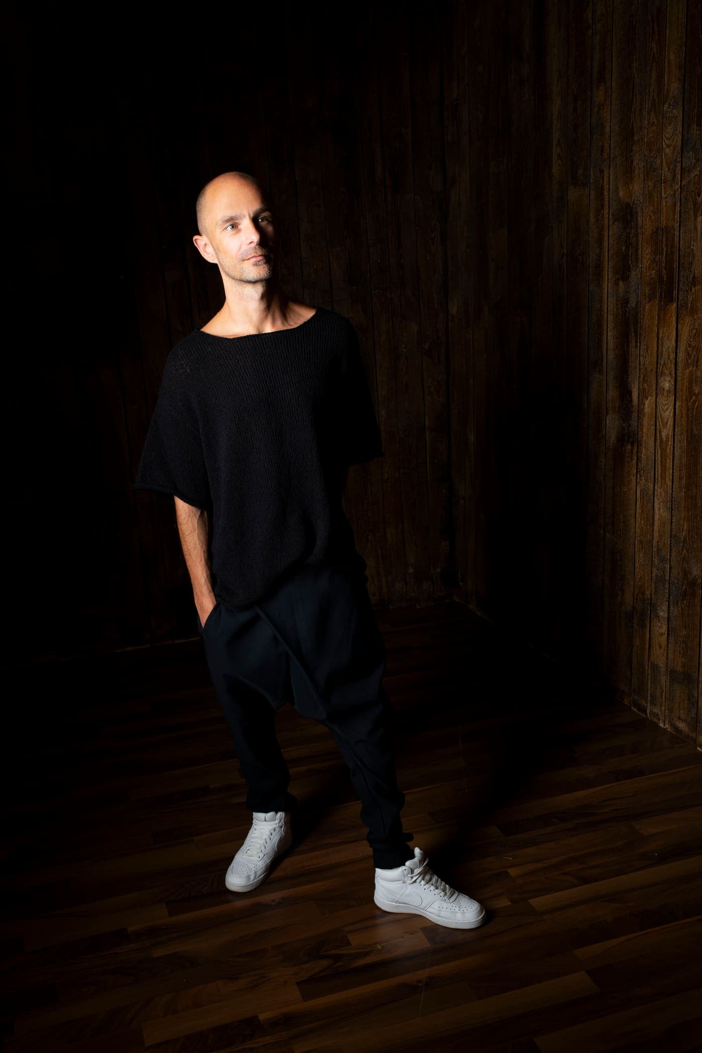 Max Hefele standing in low light, full length, dark interior