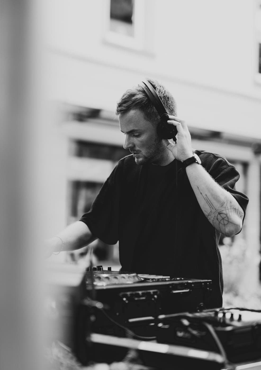 DJ richtet Kopfhörer, verschwommene Säule im Vordergrund, Schwarz-Weiß