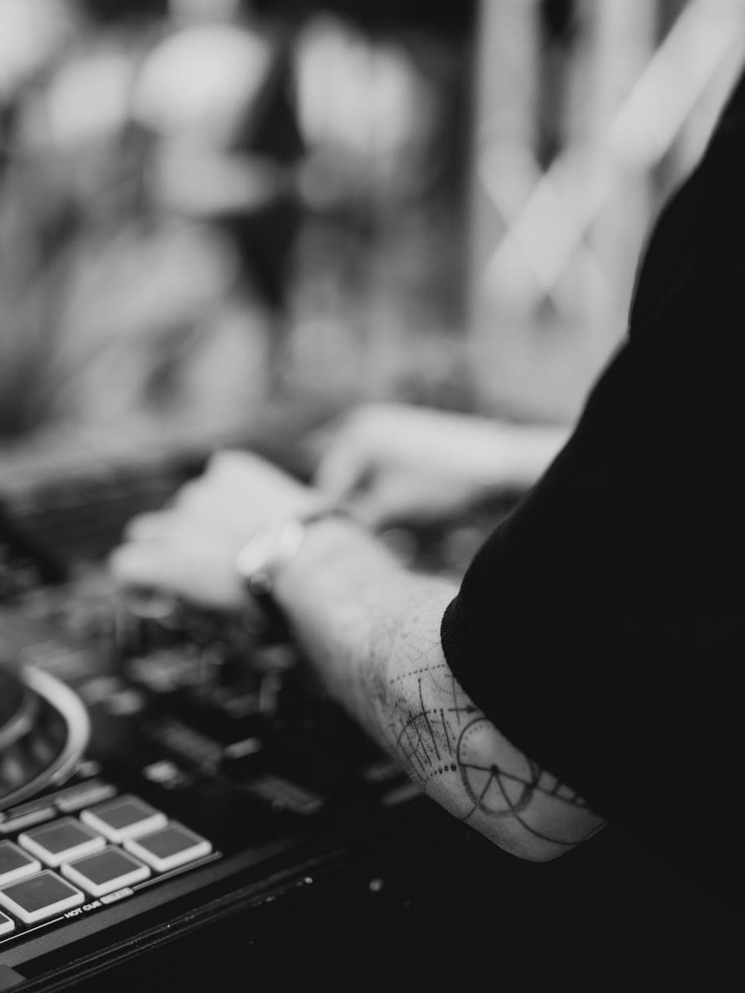 Tätowierter Unterarm an den Reglern des DJ-Pults, Nahaufnahme