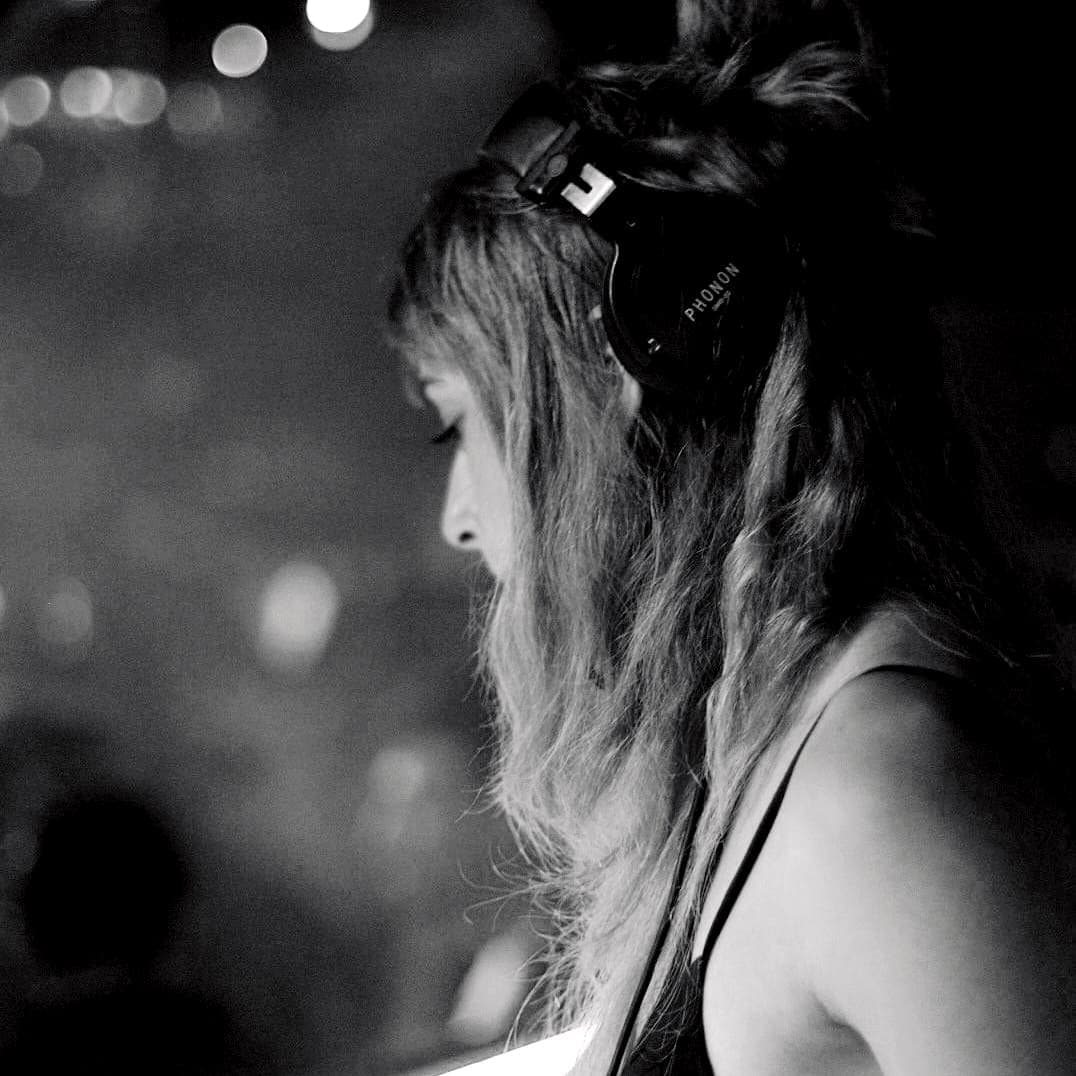 Juli Lee in headphones in a dark club, seen in profile