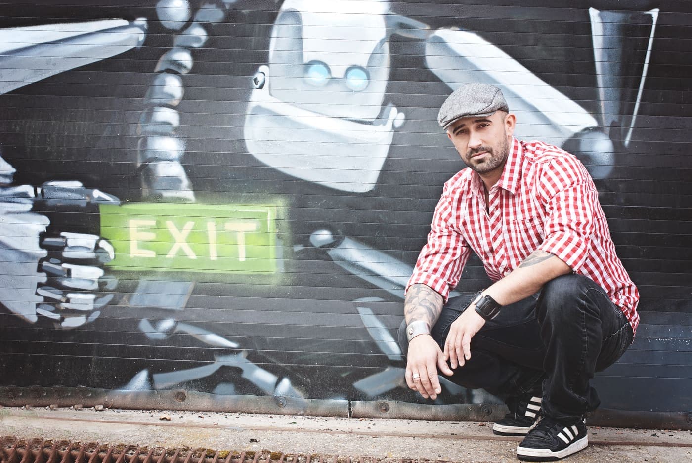 Manuel Rodriguez crouching in front of a painted wall beside an exit sign