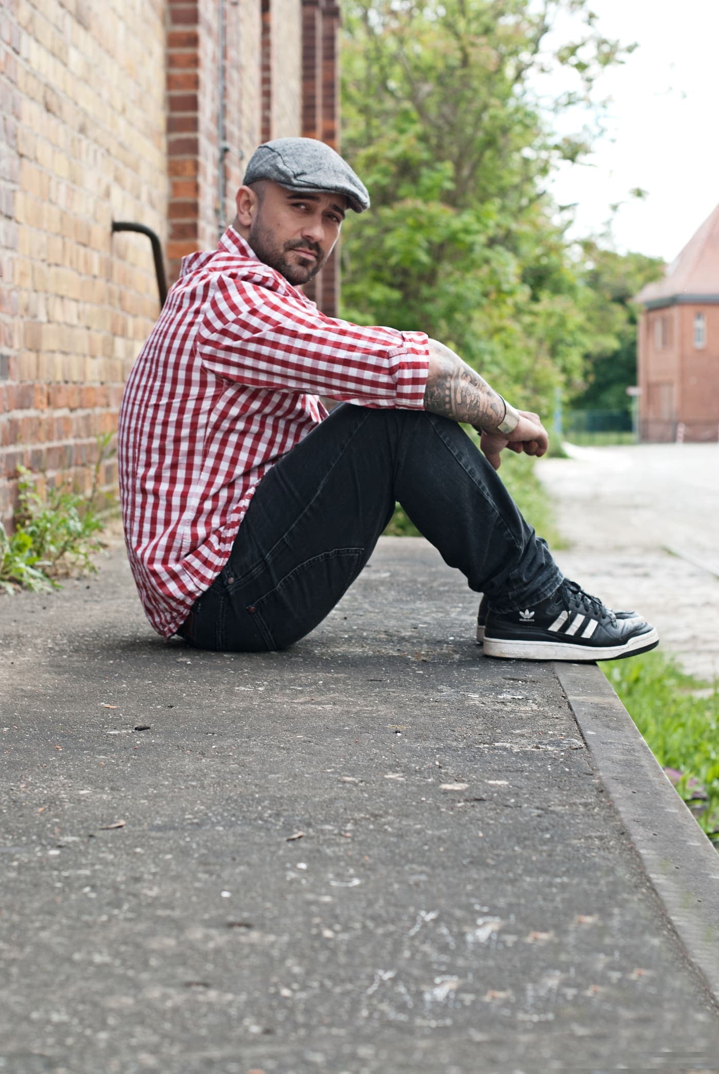 Manuel Rodriguez sitting against a brick wall on a pavement
