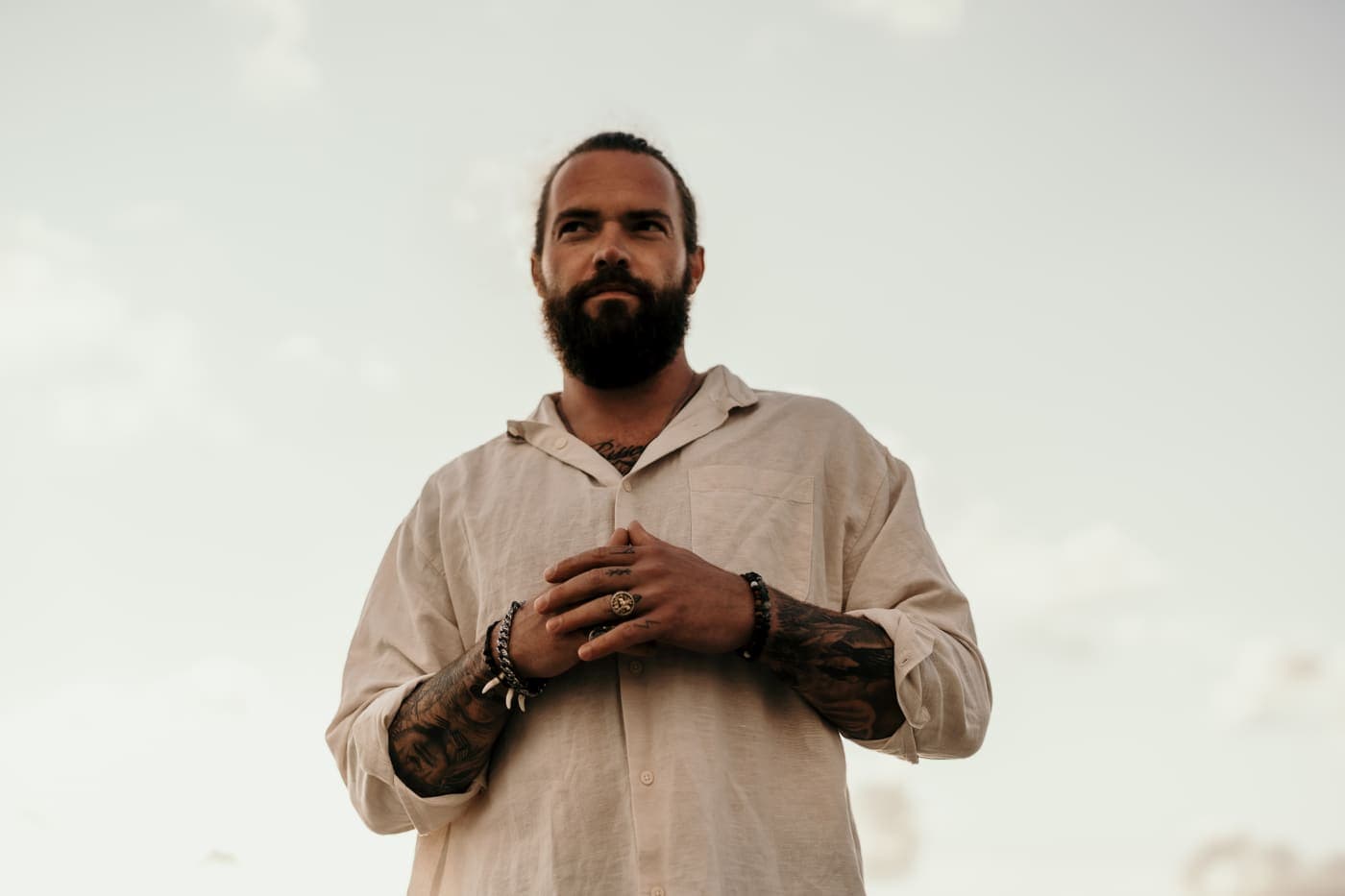 Mario Navajo on a beach at dusk, hands folded, facing the camera