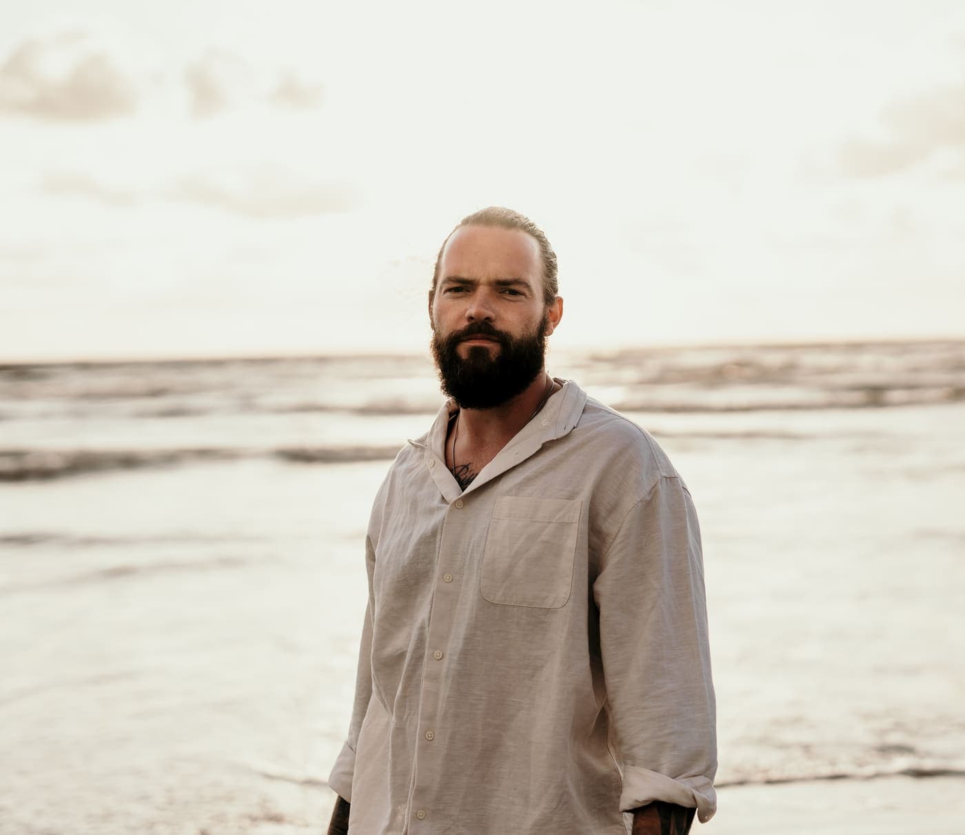 Mario Navajo in a linen shirt at the waterline, sea behind him